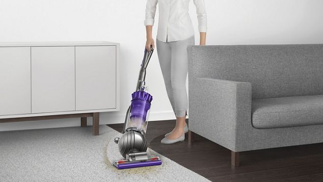 Dyson Ball Animal 2 upright vacuum cleaner manoeuvring around furniture to clean floor.