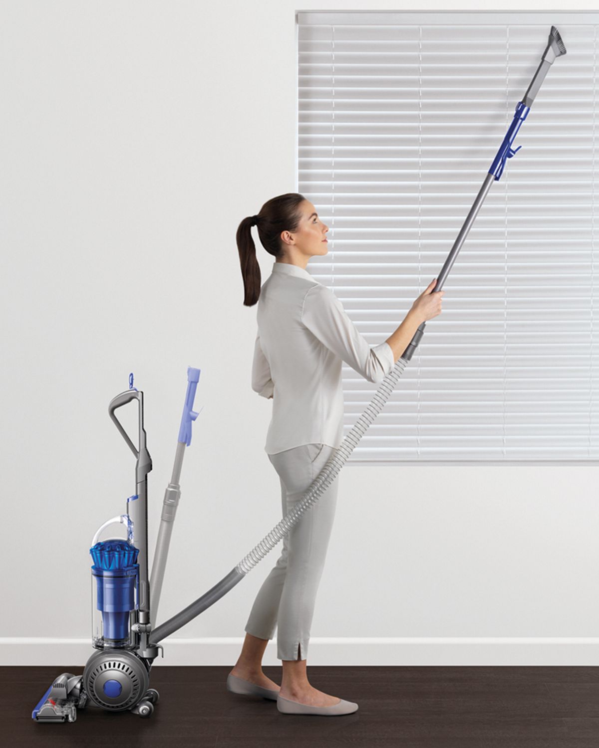 Dyson Ball Total Clean upright vacuum cleaner being used to clean household blinds. 