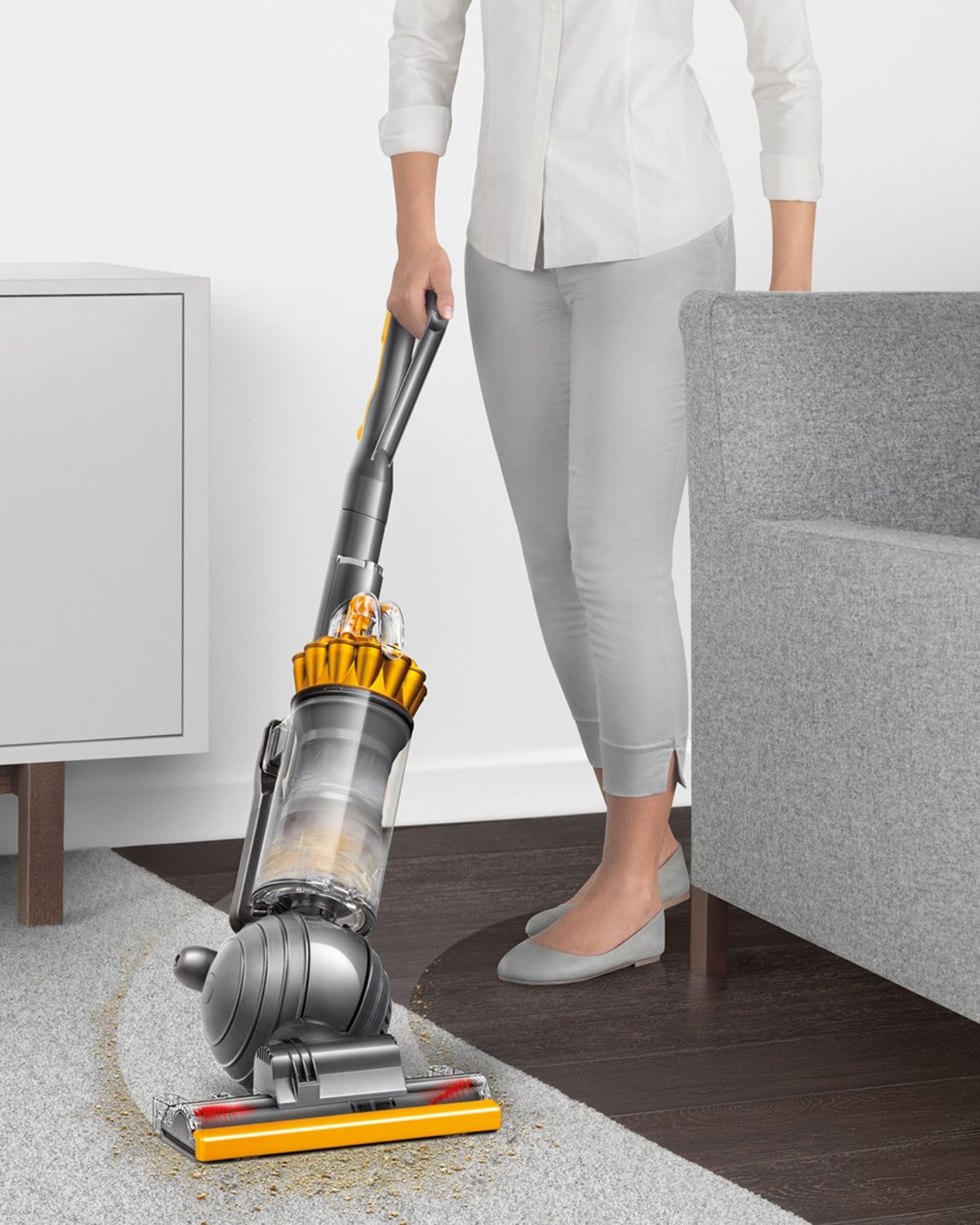 Dyson Ball Multifloor 2 upright vacuum cleaner manoeuvring around furniture to clean floor.