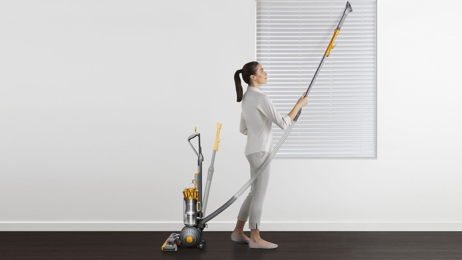 Dyson Ball Multifloor 2 upright vacuum cleaner being used to clean household blinds.