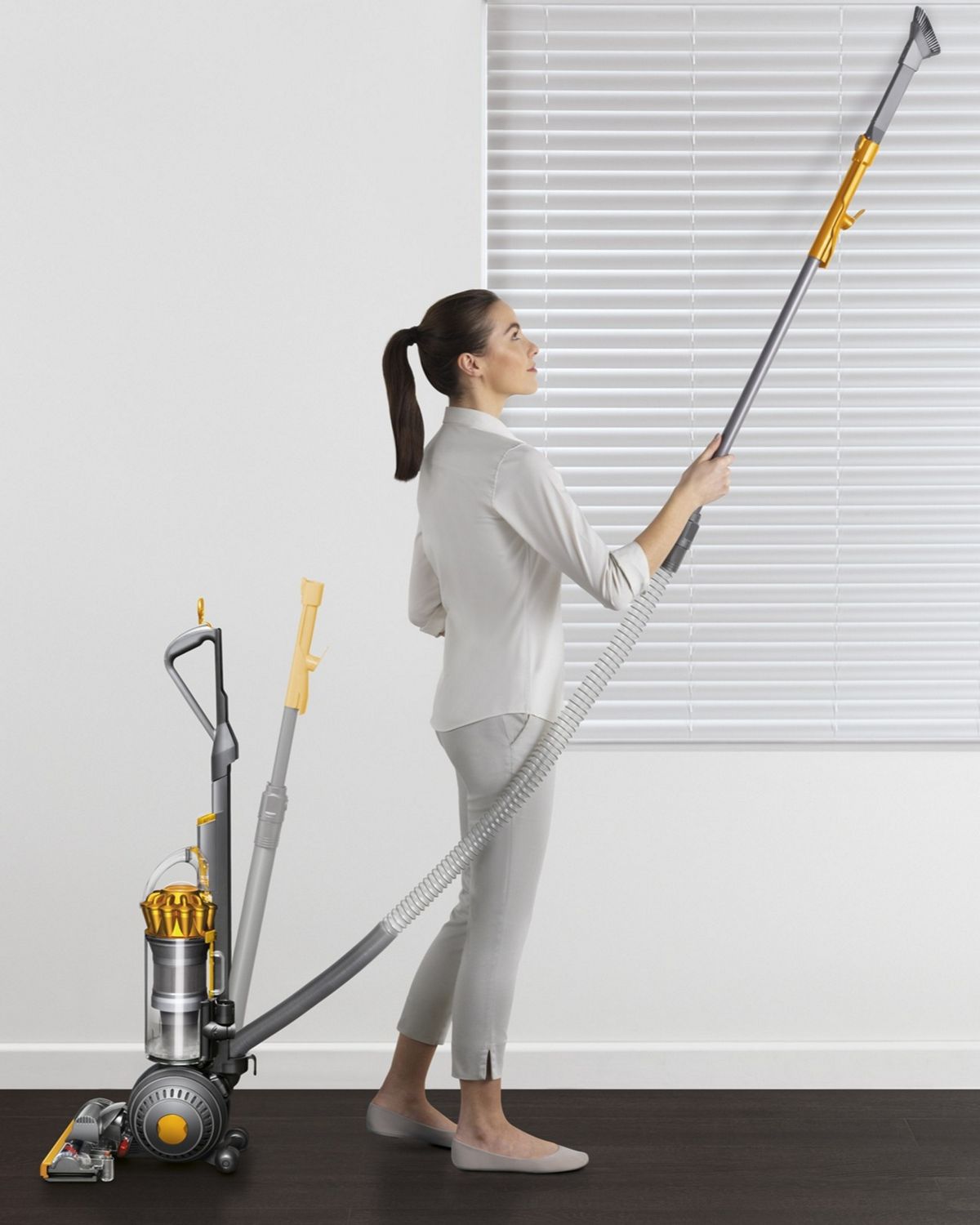 Dyson Ball Multifloor 2 upright vacuum cleaner being used to clean household blinds. 