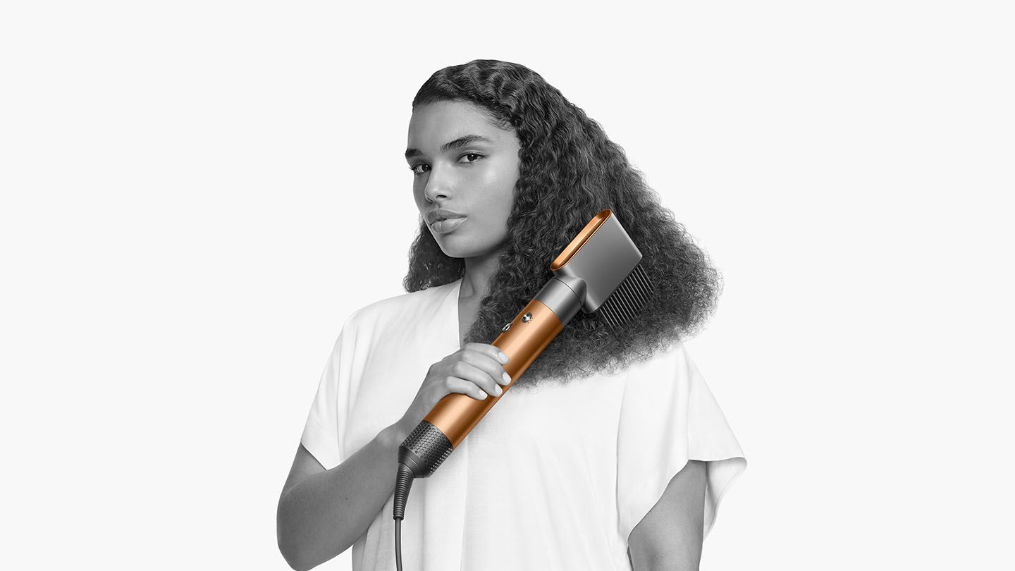 Woman curling her hair with the Dyson Airwrap Complete wide tooth comb