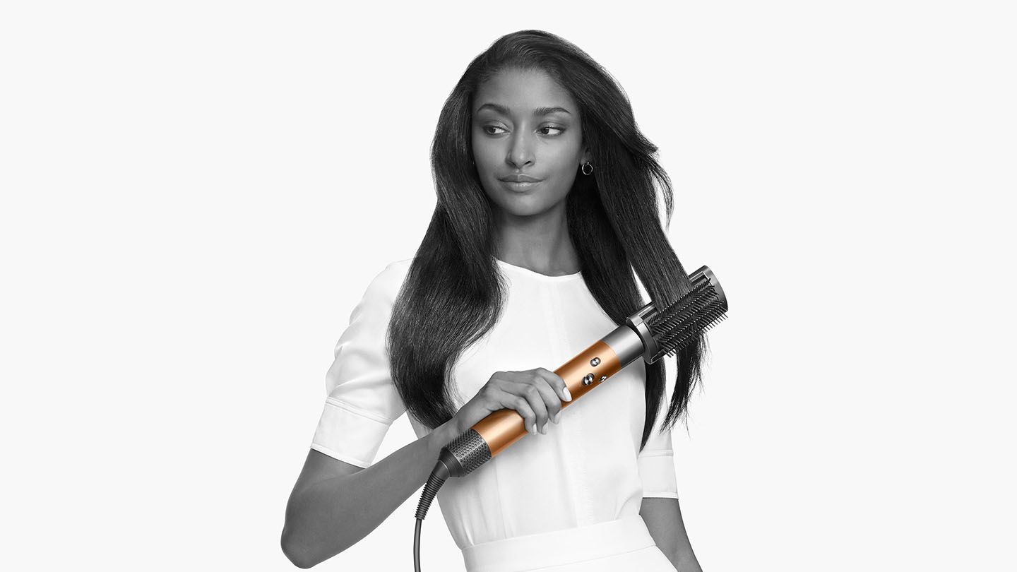 Woman straightening her hair with the Dyson Airwrap Complete brush