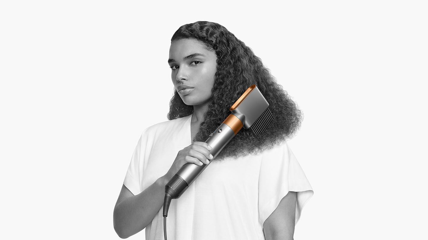 Woman curling her hair with the Dyson Airwrap Complete wide tooth comb