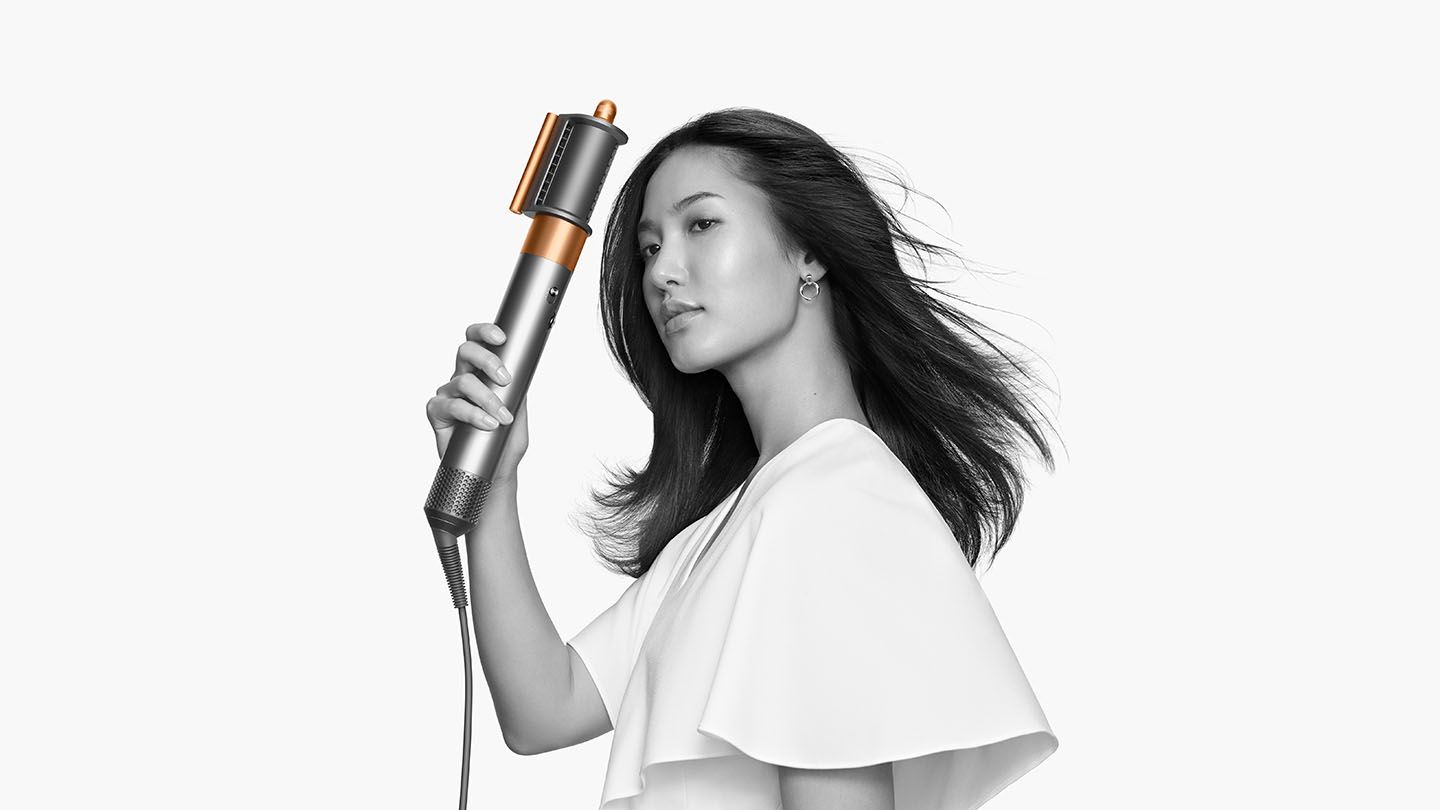 Woman straightening her hair with the Dyson Airwrap Complete pre-styling dryer