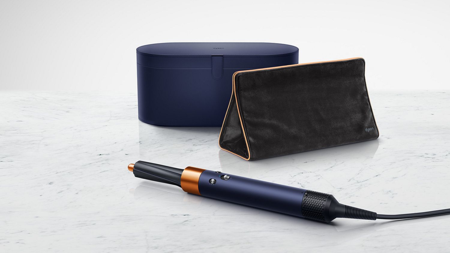 Airwrap styler laid in front of storage case and travel bag 