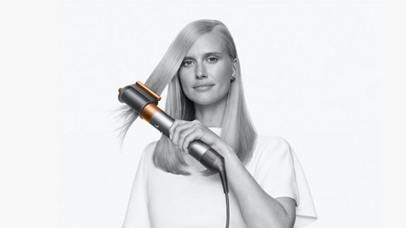 Woman smoothing flyaways with the Dyson Airwrap Origin pre-styling dryer