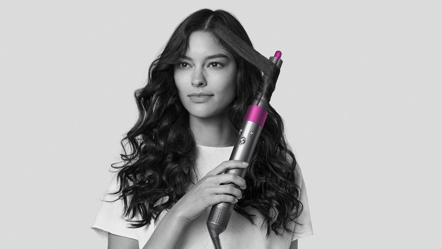 Woman using Dyson Airwrap styler to curl her hair.