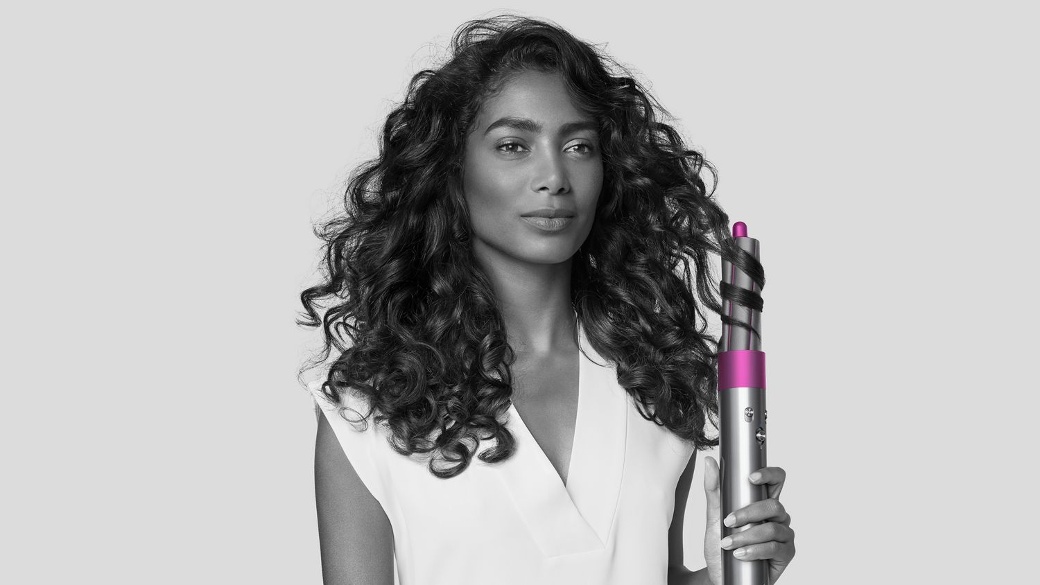 Woman using Dyson Airwrap styler to curl her hair.