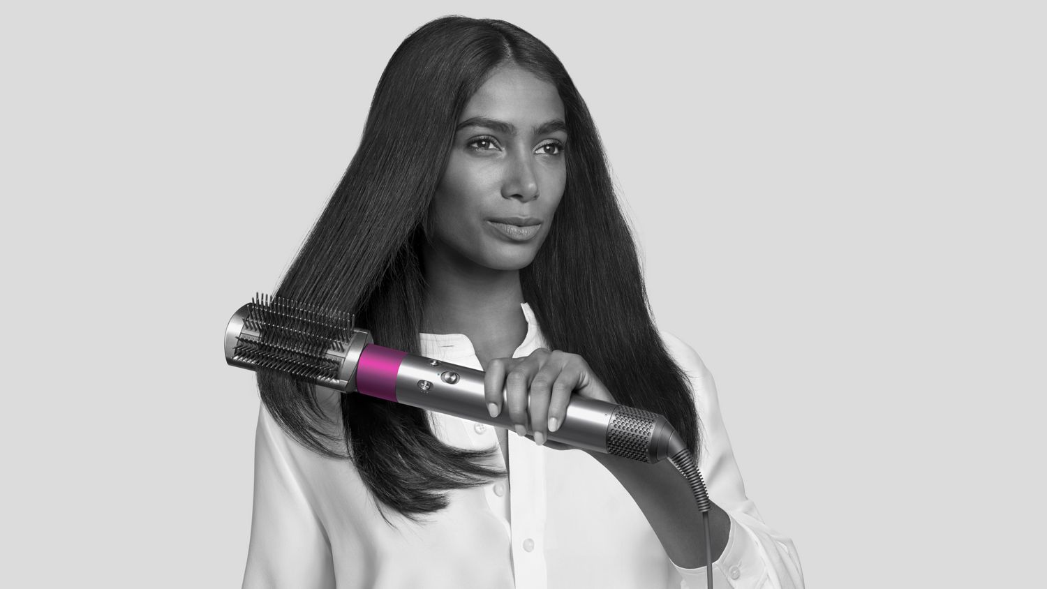 Woman using Dyson Airwrap styler with firm smoothing brush attached. 