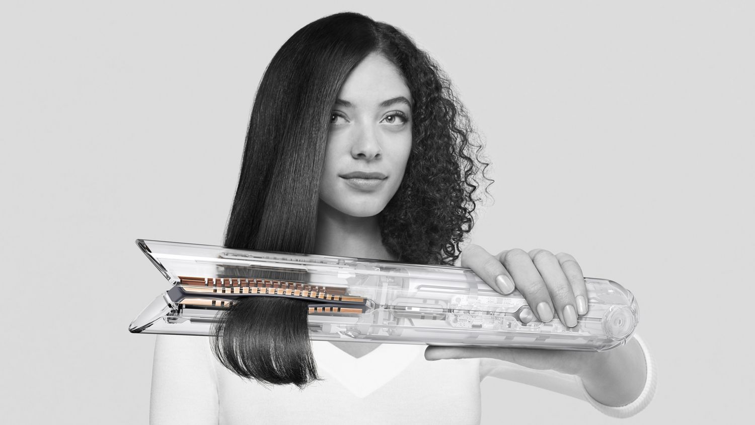 Woman using Dyson Corrale straightener with inner technology of the machine exposed.