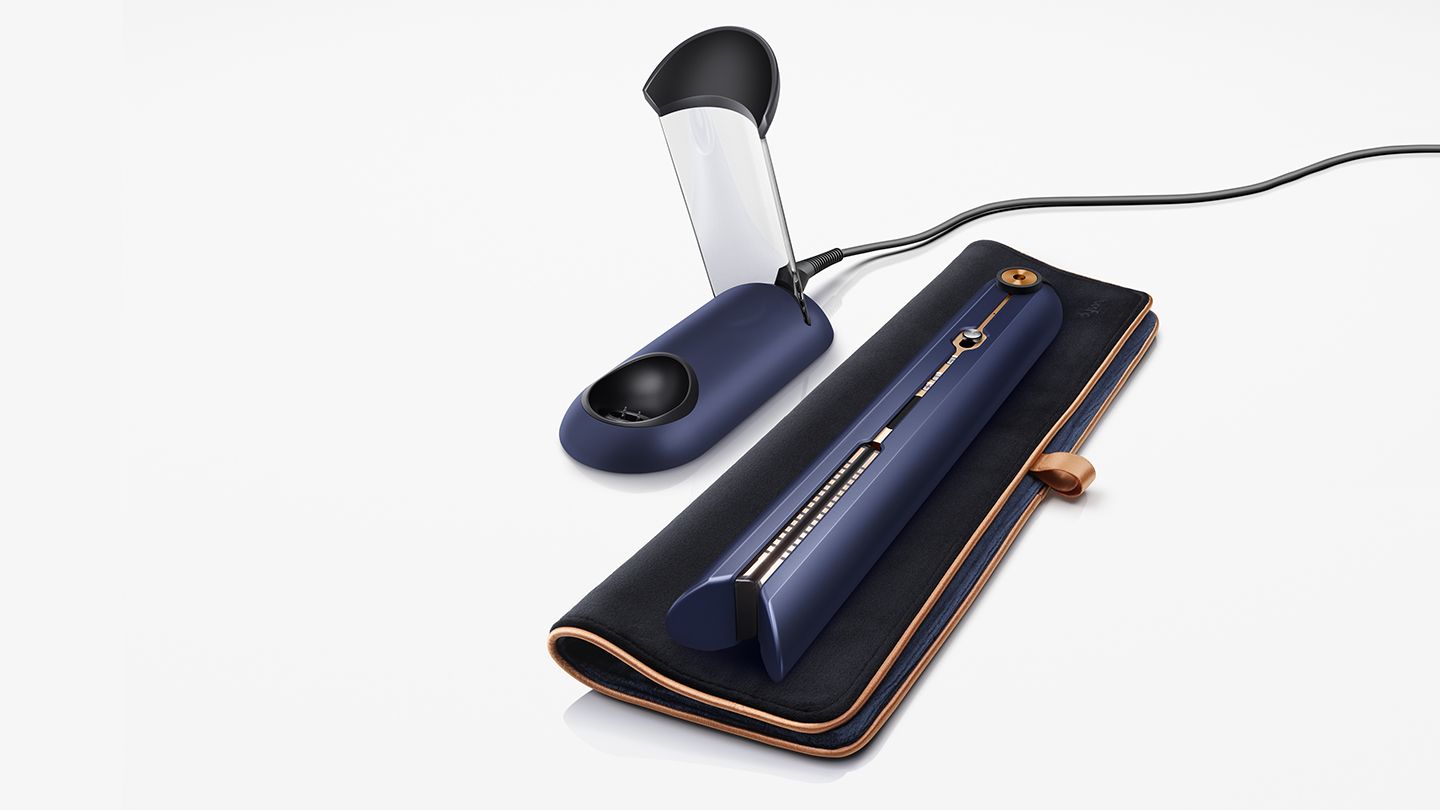 Dyson Corrale placed on travel bag next to charging dock