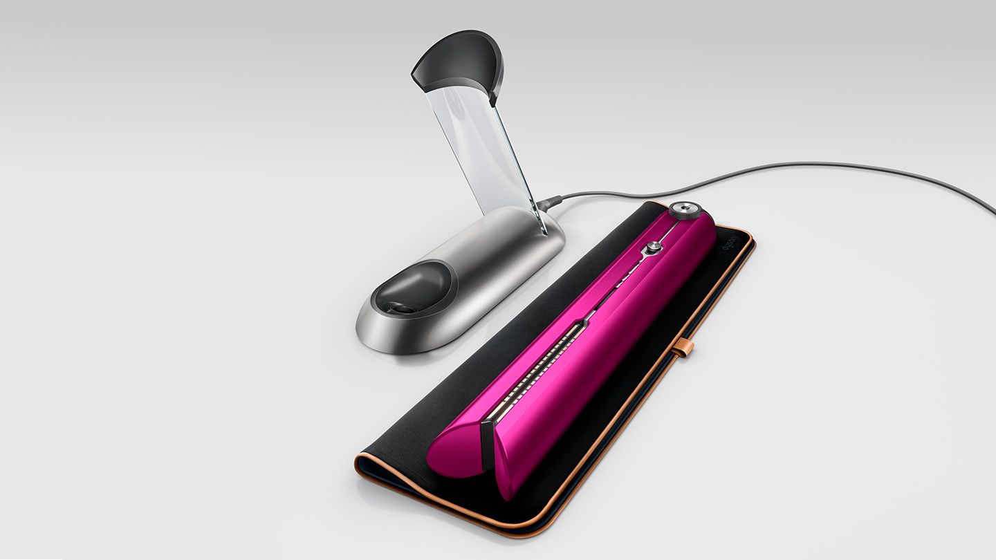 Dyson Corrale placed on travel bag next to charging dock