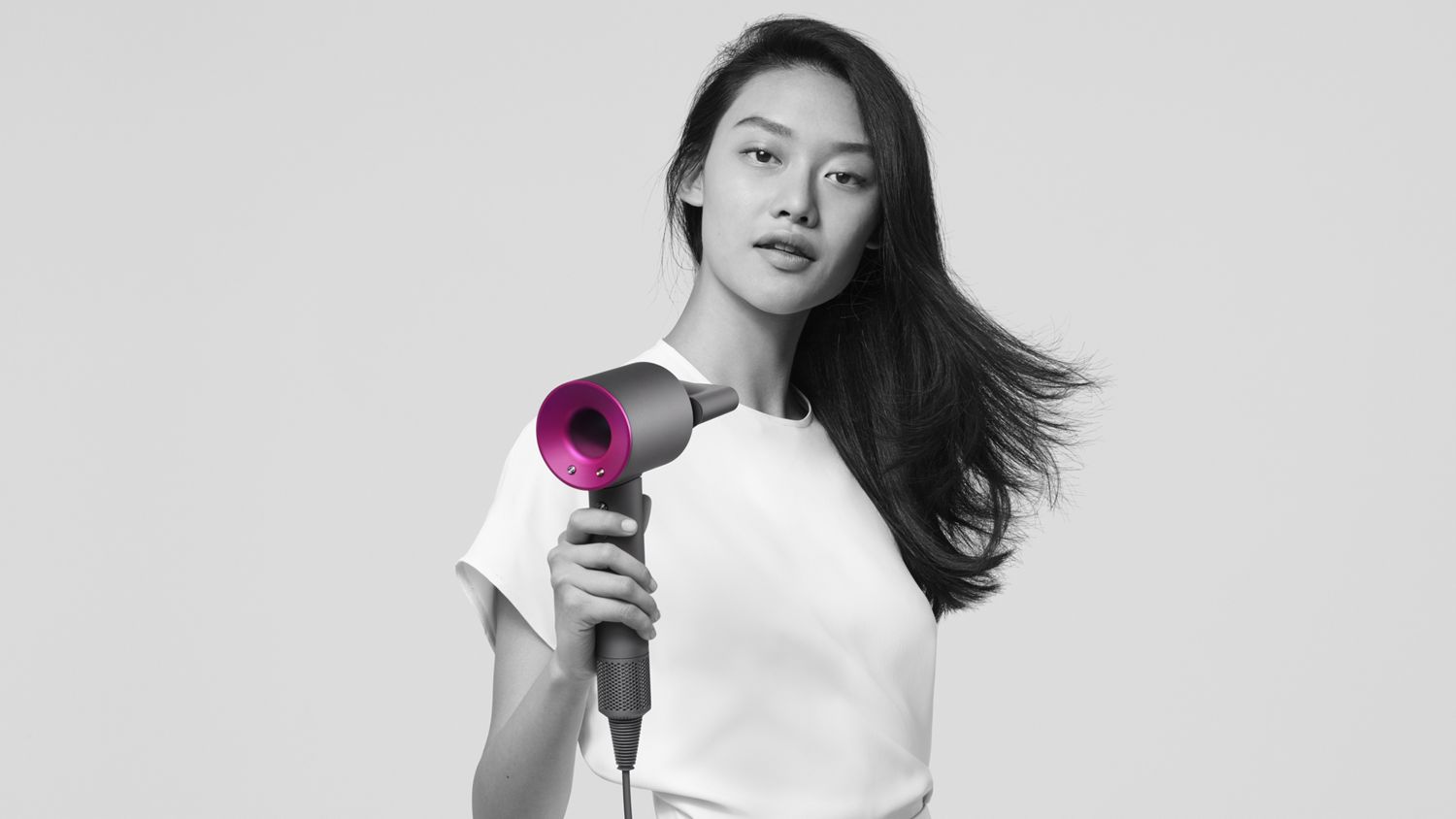 Woman holding Dyson Supersonic hair dryer with smoothing nozzle attached