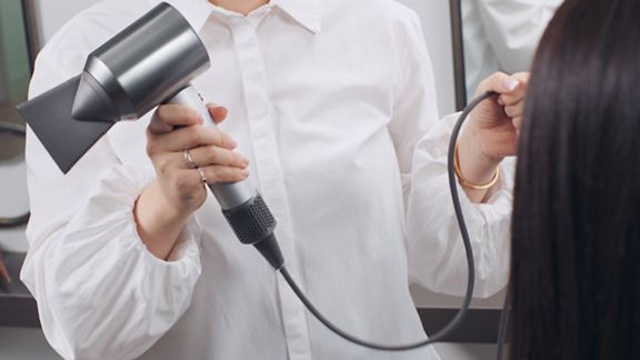 Woman holding Dyson Supersonic Professional hair dryer 