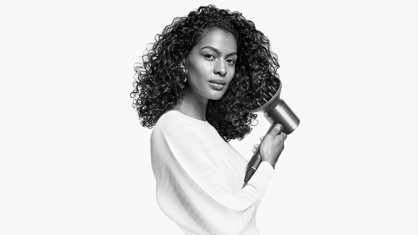 Woman holding Dyson Supersonic hair dryer with diffuser attachment