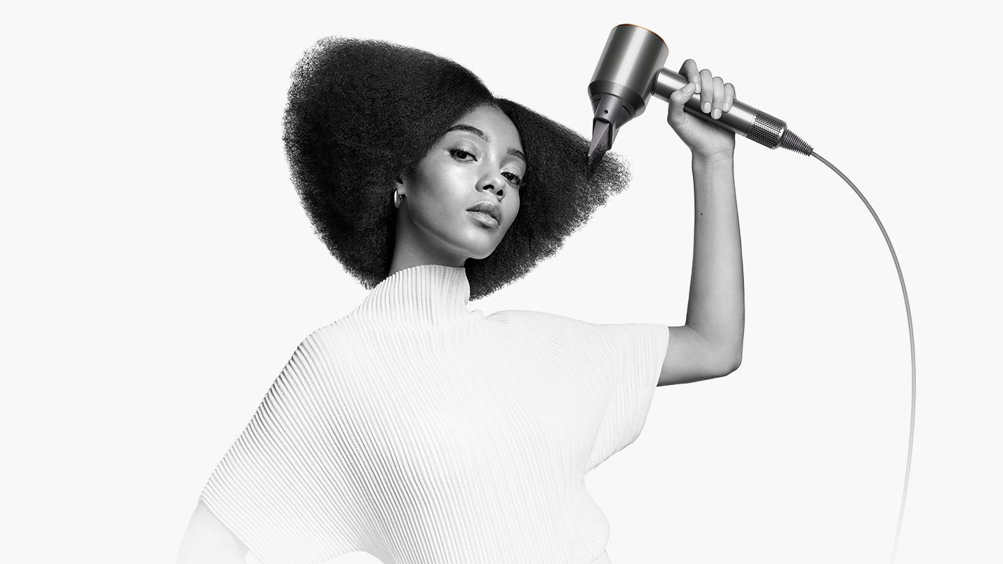 Woman holding Dyson Supersonic hair dryer with styling concentrator attachmentt