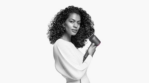 Woman holding Dyson Supersonic hair dryer with diffuser attachment