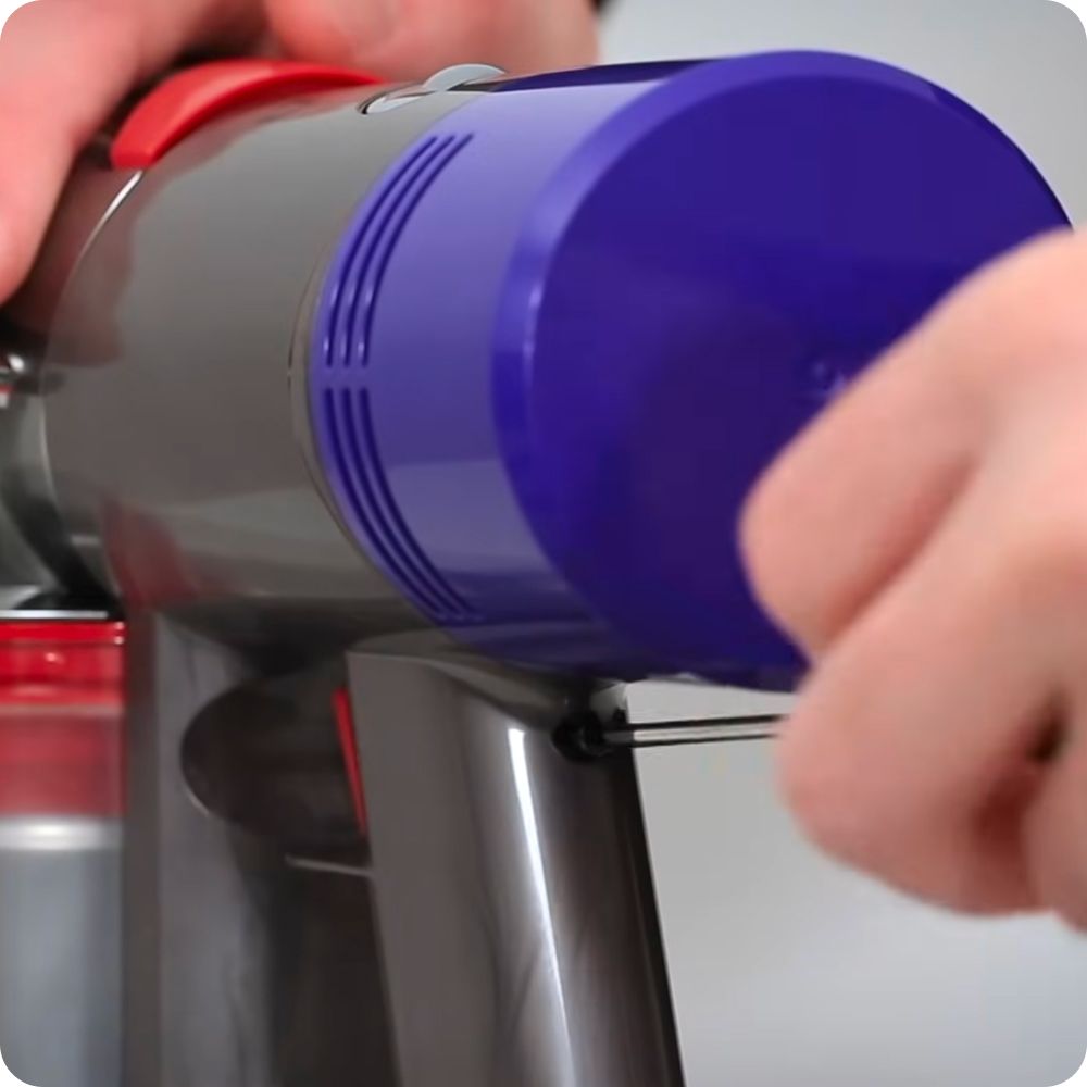 The battery is unscrewed from the handle of a Dyson cordless vacuum.