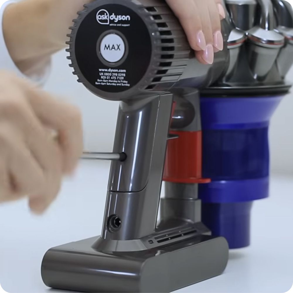 The battery is unscrewed from the handle of a Dyson cordless vacuum.