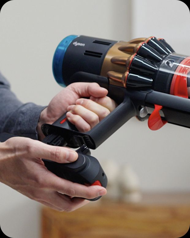 A battery is clicked into place on the handle of a Dyson vacuum cleaner.