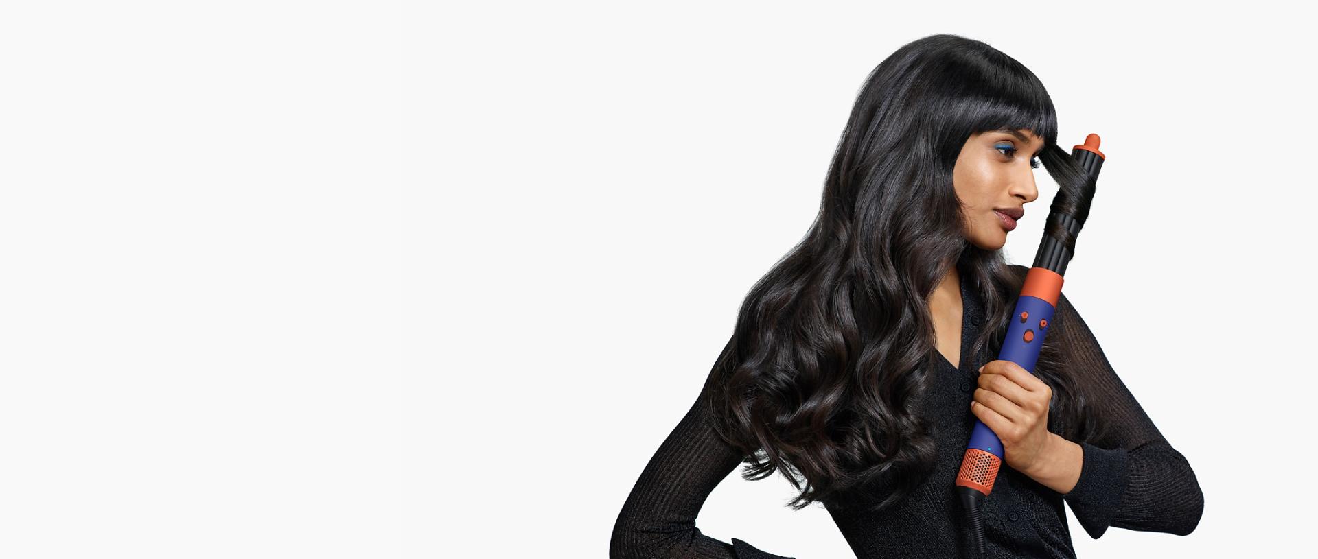 A model is curling her hair with an Airwrap ID multi-styler and dryer.