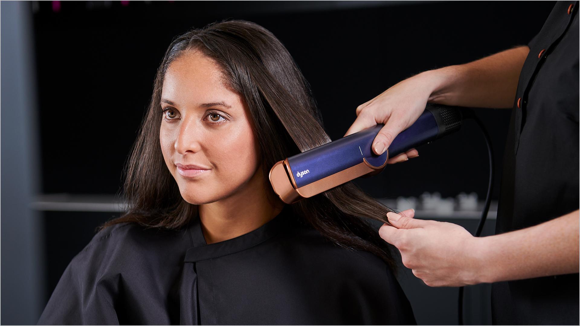 A customer in the Dyson Demo Store tries out the Dyson Airstrait straightener, helped by a Dyson Expert.