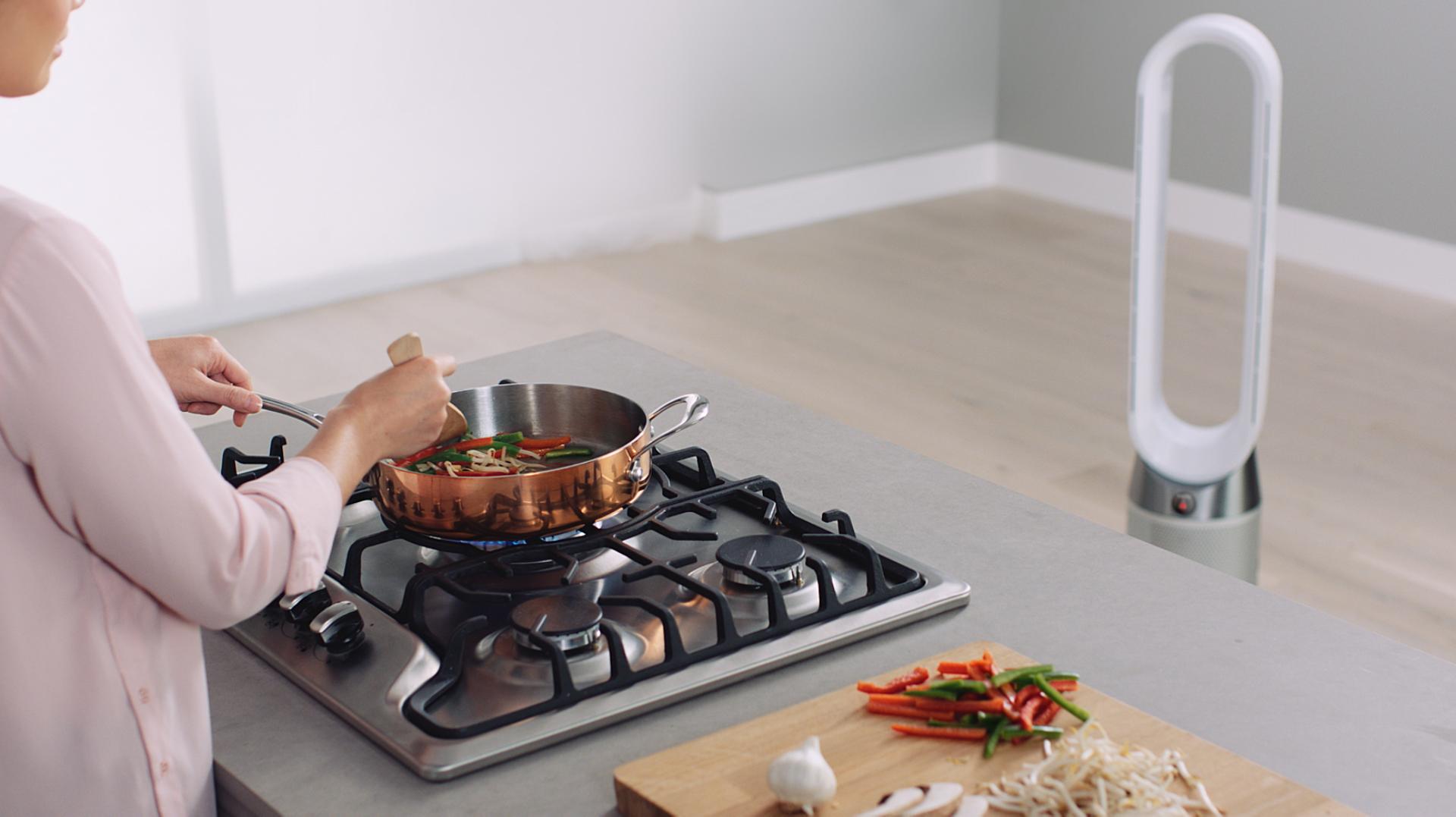 person cooking in kitchen with Dyson Pure Cool Tower capturing pollutants