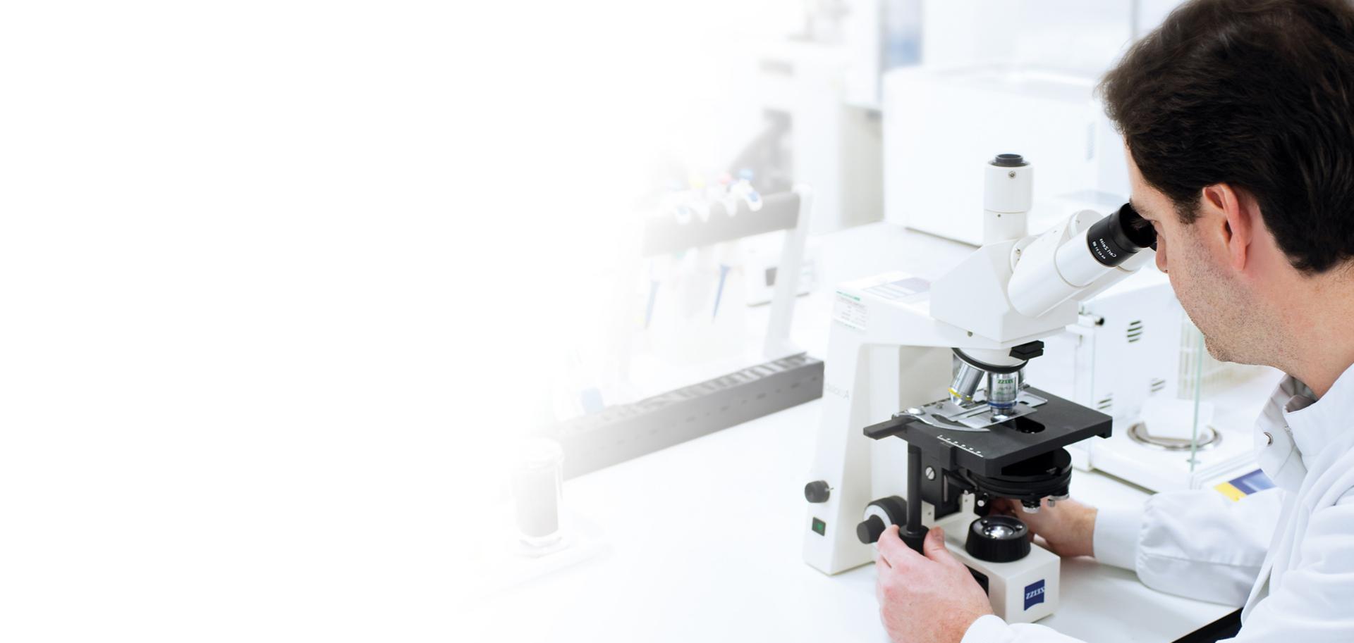 Man looking through microscope at dust particles