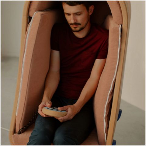 A man sat in chat holding device.