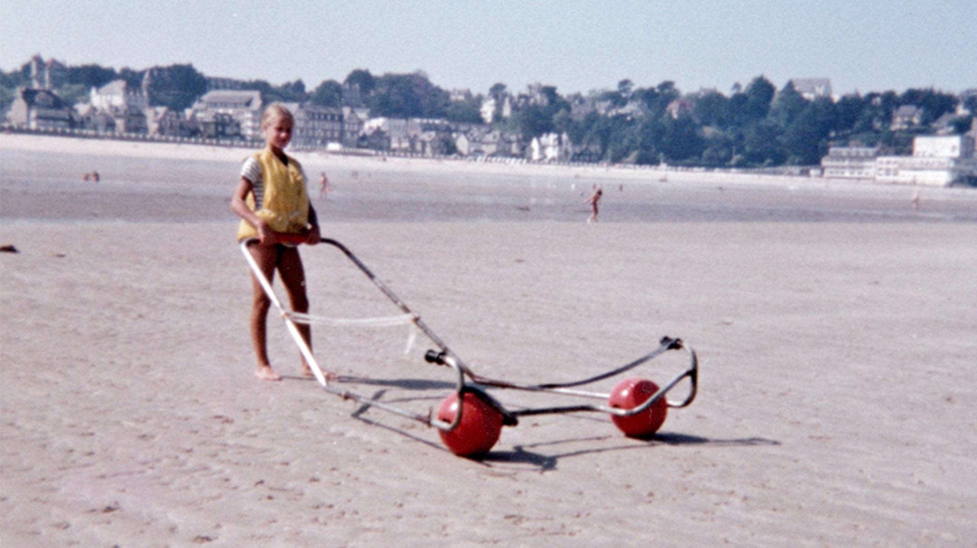 A young girl standing on a Provence beach holding the Trolleyball frame