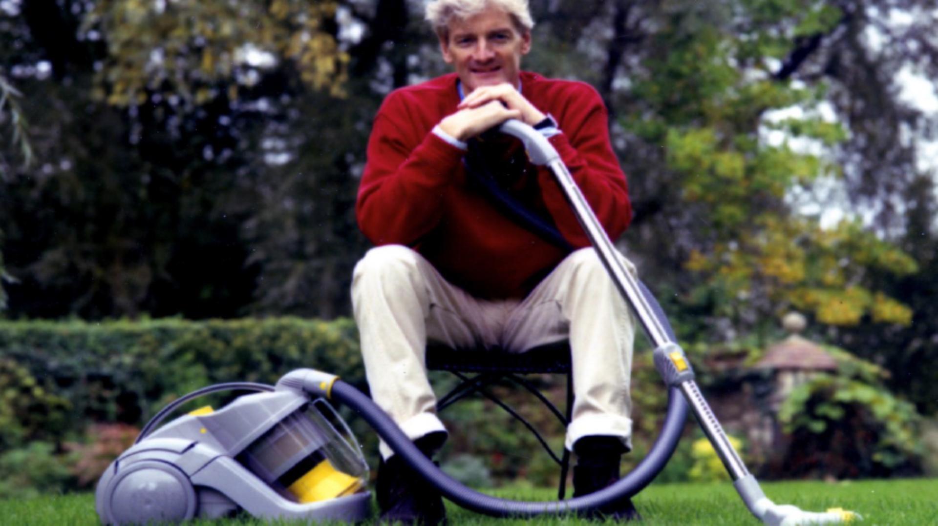 James Dyson sitting outside in a garden, leaning on the DC02 vacuum