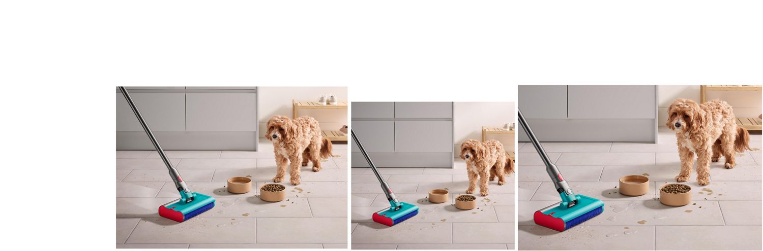 Dog stares past food and water bowl as Dyson Submarine wet roller head cleans up crumbs and spilt water across the kitchen floor.
