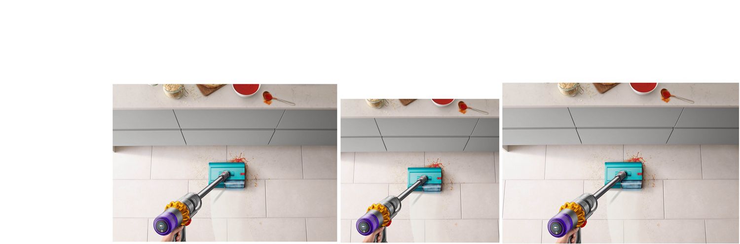 Dyson V15s Detect Submarine wet roller head clearing up spilt soup and breadcrumbs on a tiled kitchen floor near a countertop.