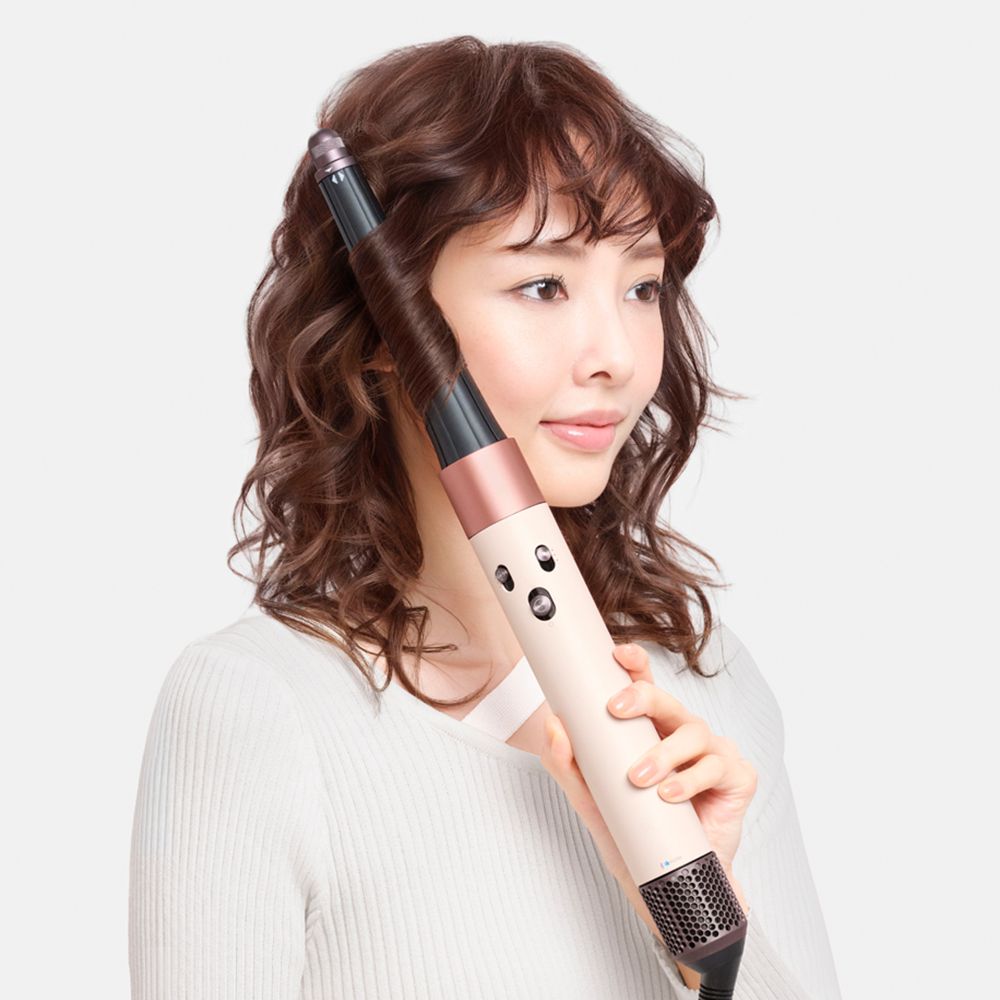 Model with long hair being blown upwards by dryer.