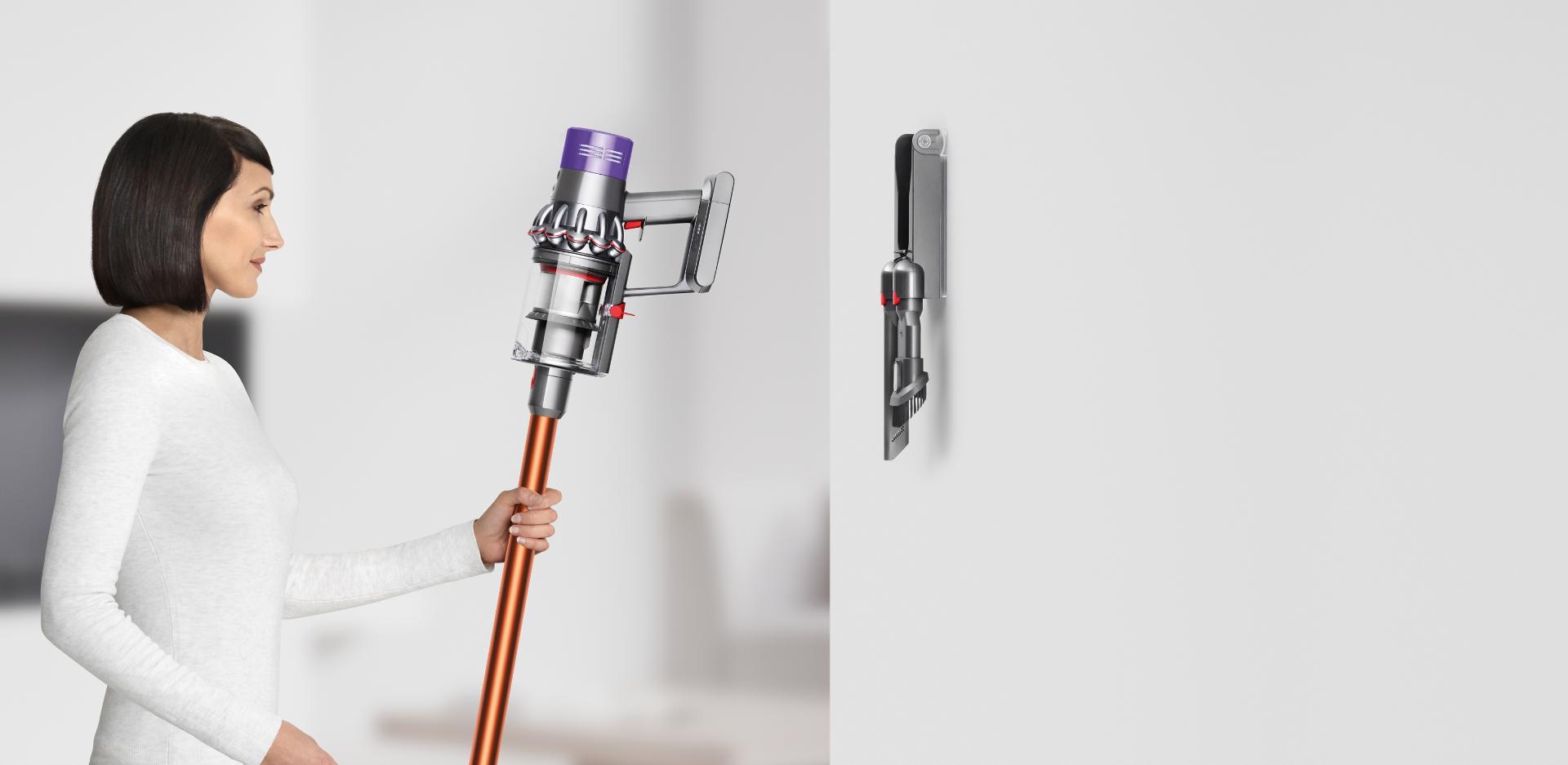 Woman placing Dyson Cyclone V10™ vacuum into wall dock