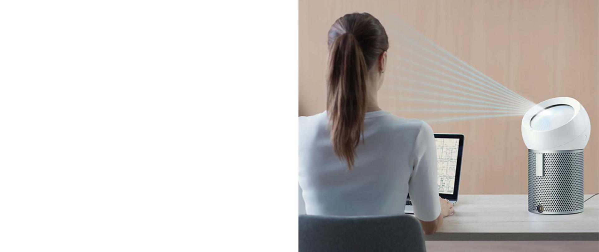 Kobieta siedząca przy biurku z oczyszczaczem Dyson Pure Cool Me