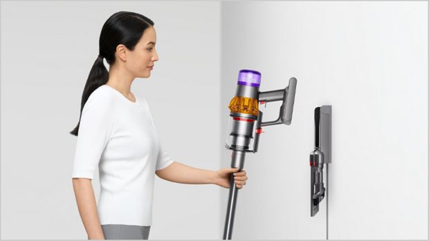 Woman placing Dyson vacuum into the wall dock