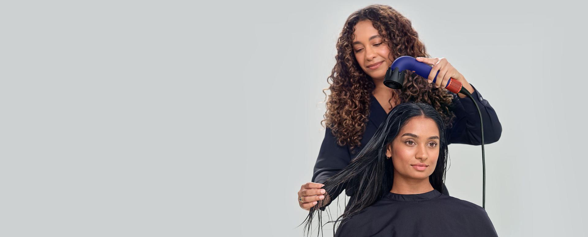 Model having their hair dried and styled by a Dyson Global Styling Ambassador with a Dyson Supersonic r Professional hair dryer with the Powerful air attachment.