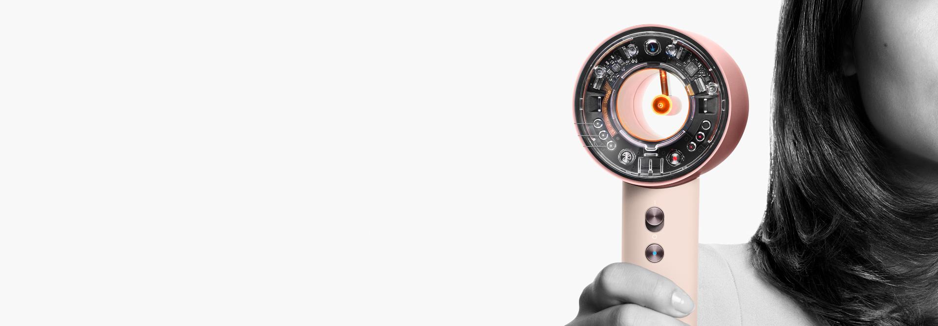 Dyson Supersonic nural saç kurutma makinesini tutan bir model.