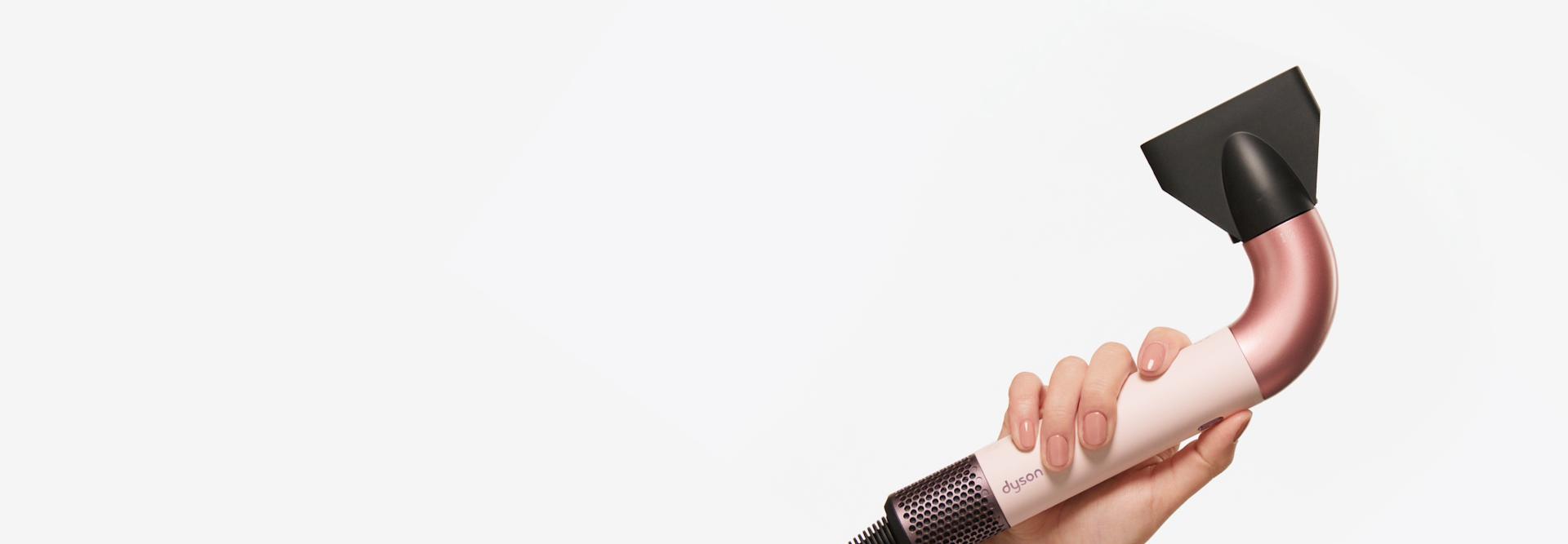 Hand picking up the Dyson Supersonic r hair dryer.