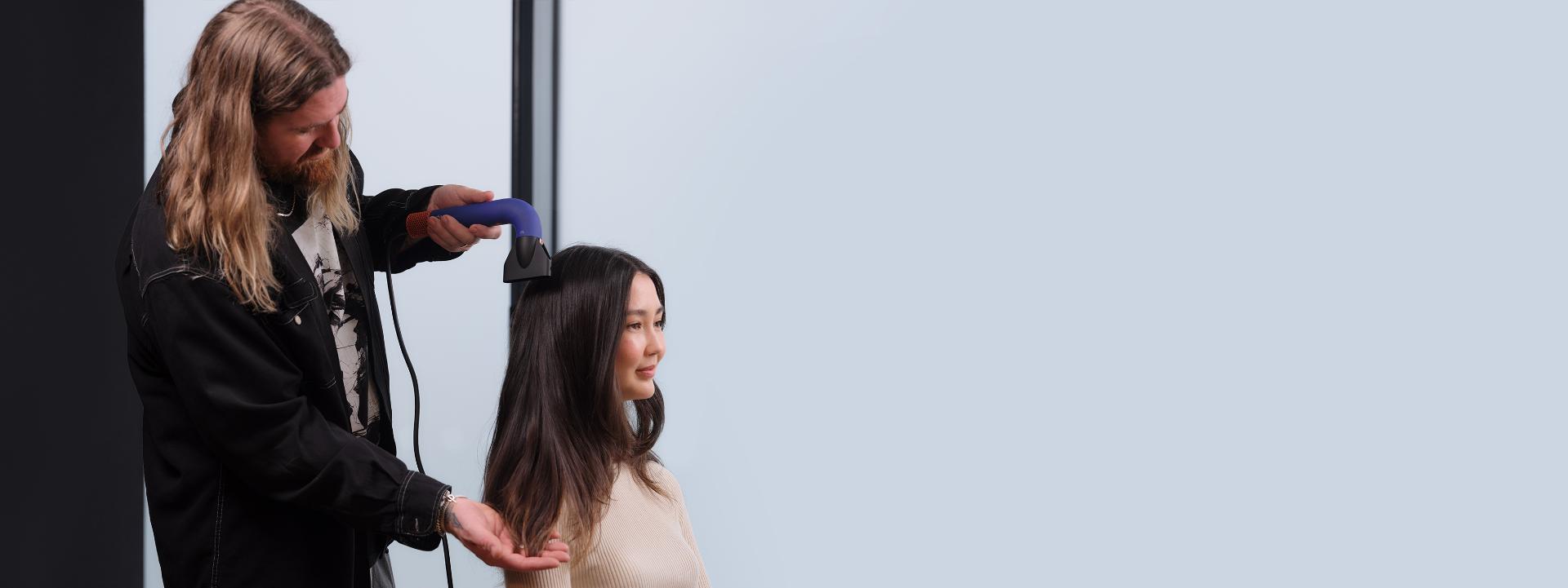 Matthew Collins styling model's hair with Dyson Supersonic r Professional hair dryer and Pro concentrator attachment.