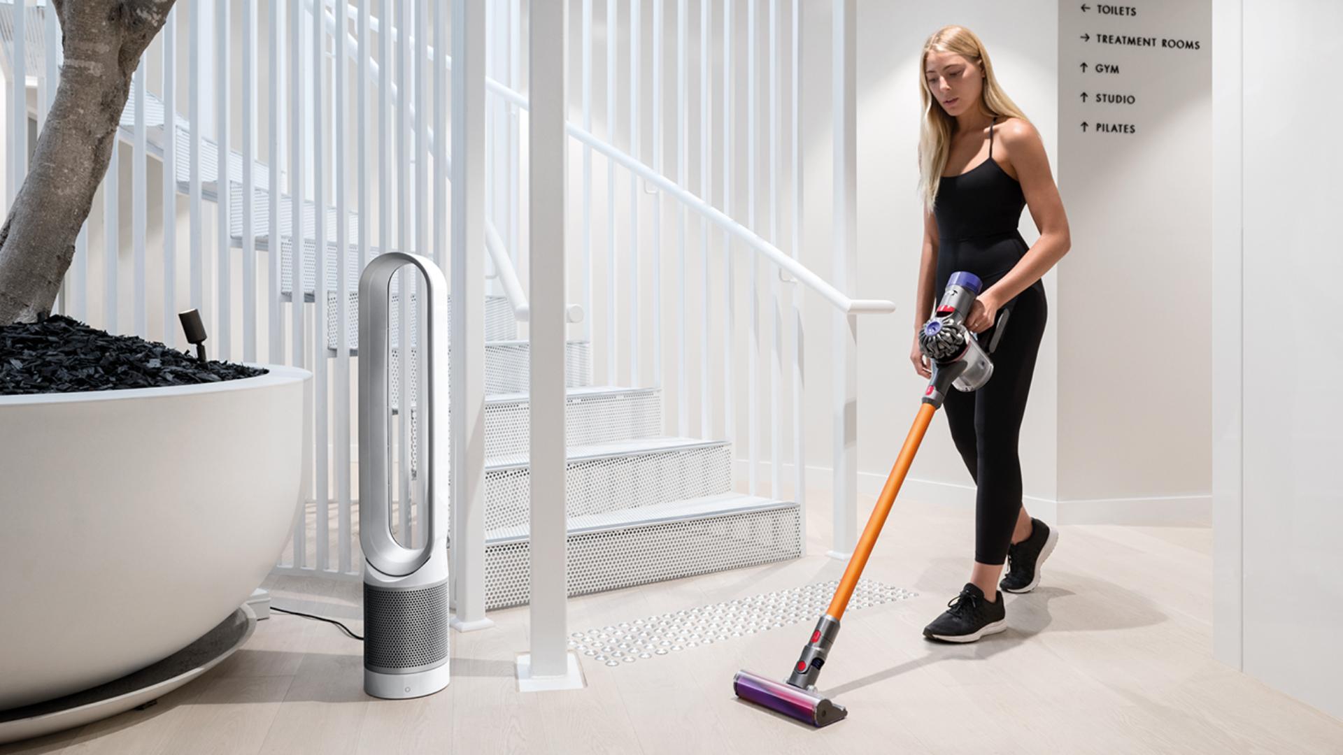 Lady cleaning The Well's floors with a Dyson V8™ by a Dyson purifier 