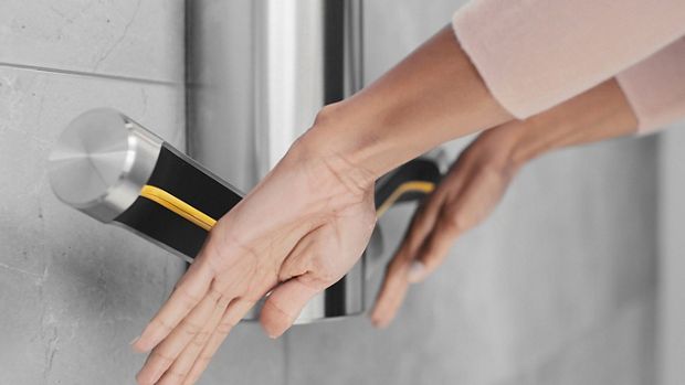 A pair of hands held out below a Dyson Airblade 9kJ hand dryer as they are dried.