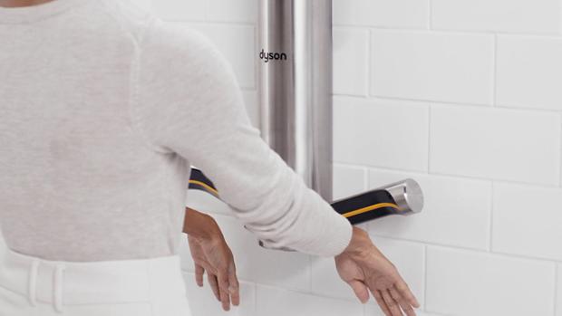 A pair of hands held out below a Dyson Airblade 9kJ hand dryer as they are dried.