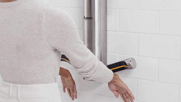 A pair of hands held out below a Dyson Airblade 9kJ hand dryer as they are dried.