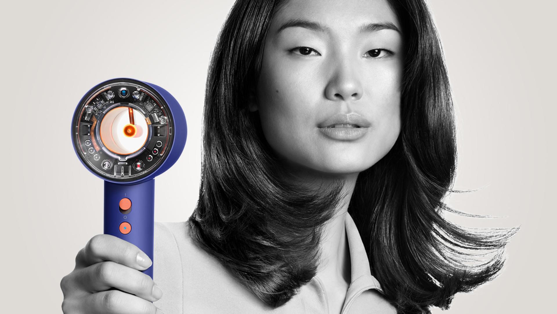 Model removing flyaways with the Dyson Supersonic hair dryer and Flyaway attachment.