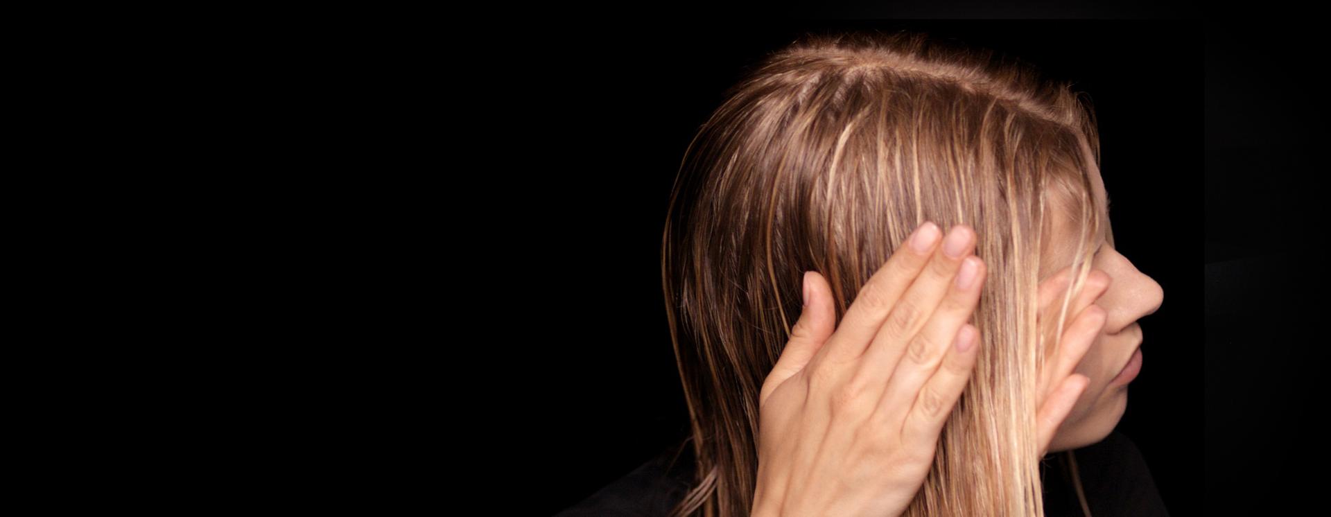 Uzun, nemli saçına elleriyle ürünü uygulayan bir model