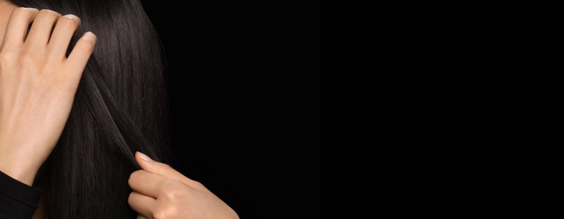 عارِضة شعرها طويل ورطب تَستخدم يديها لتنعيم المستحضر على امتداد طول الشعر