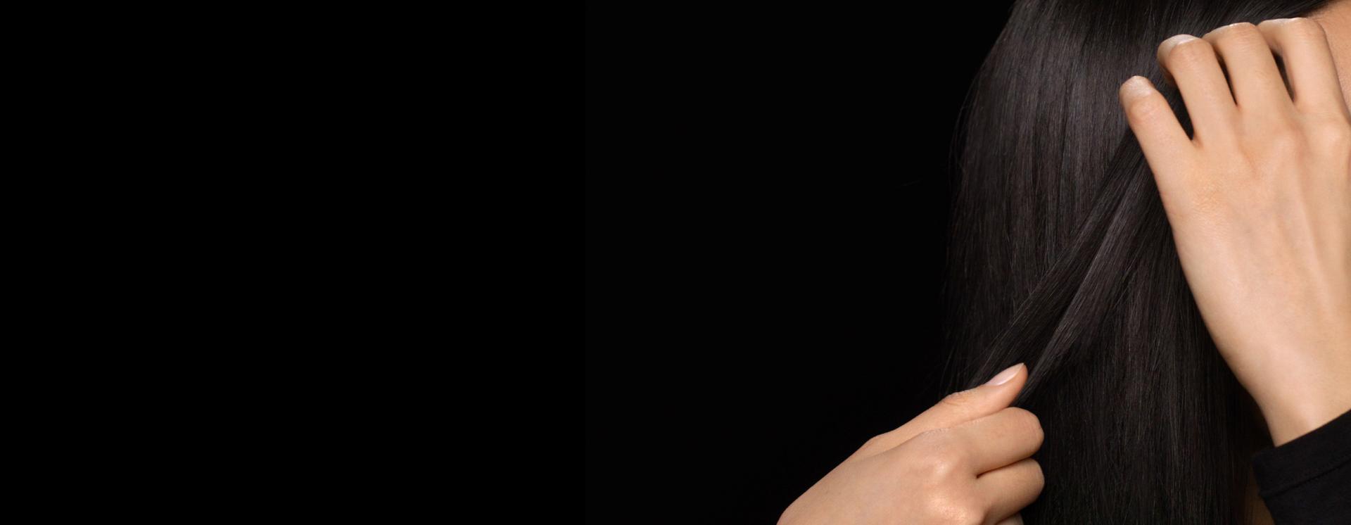 A model with long, damp hair uses her hands to smooth product through the lengths